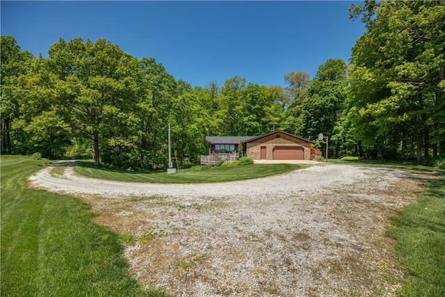 view of front of house featuring a view of trees, a garage, a front lawn, and driveway