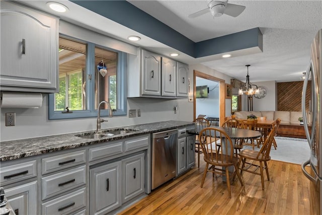 kitchen with a sink, gray cabinetry, appliances with stainless steel finishes, a ceiling fan, and light wood-style floors