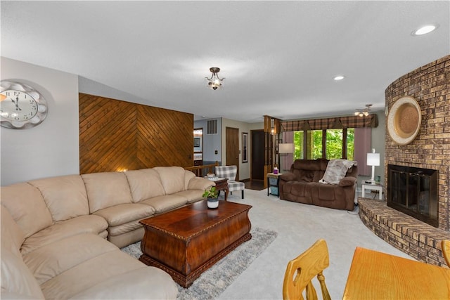 carpeted living room featuring wood walls, a brick fireplace, recessed lighting, and an accent wall