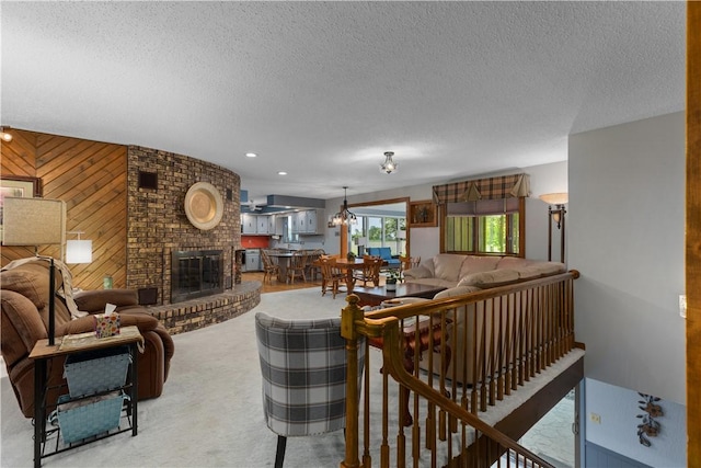 living area with a textured ceiling, a fireplace, carpet flooring, and wooden walls