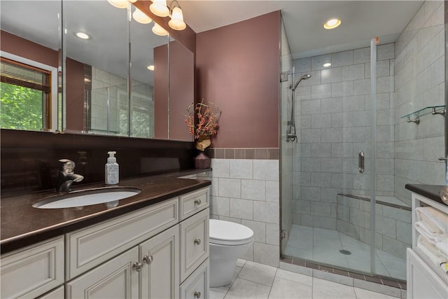 bathroom featuring tile walls, a stall shower, tile patterned flooring, toilet, and vanity