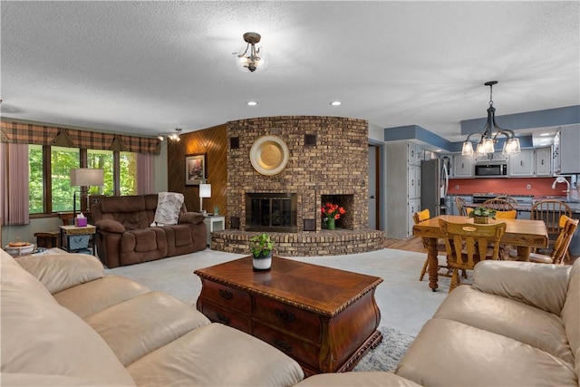 living room with a chandelier, a brick fireplace, a textured ceiling, and light carpet