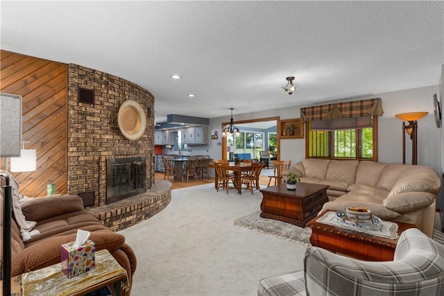 living room featuring wooden walls, a textured ceiling, carpet, a fireplace, and recessed lighting