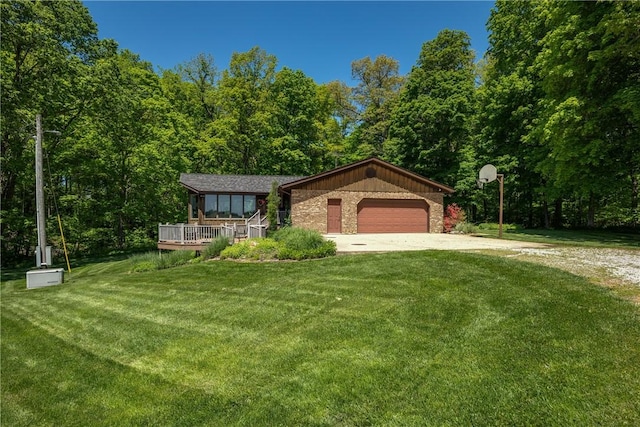 view of front facade featuring driveway, a front yard, a garage, and a forest view