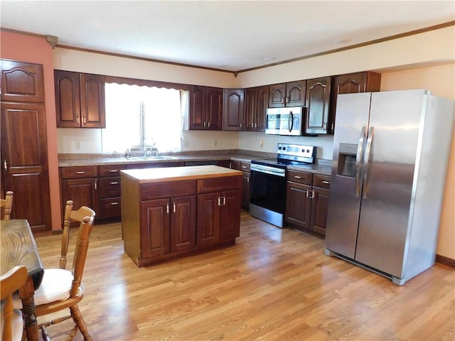 205 Monroe St, Toledo, IL 62468 - kitchen featuring appliances with stainless steel finishes, ornamental molding, light wood-style flooring, a center island, and dark brown cabinets