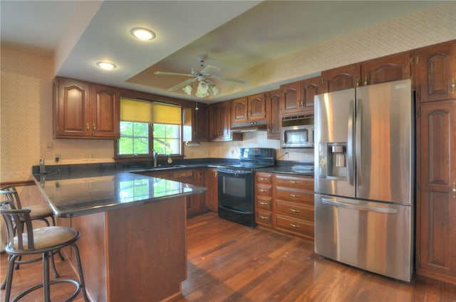 1225 W Pineview Ct, Decatur, IL 62526 - kitchen featuring appliances with stainless steel finishes, wallpapered walls, under cabinet range hood, a peninsula, and dark countertops