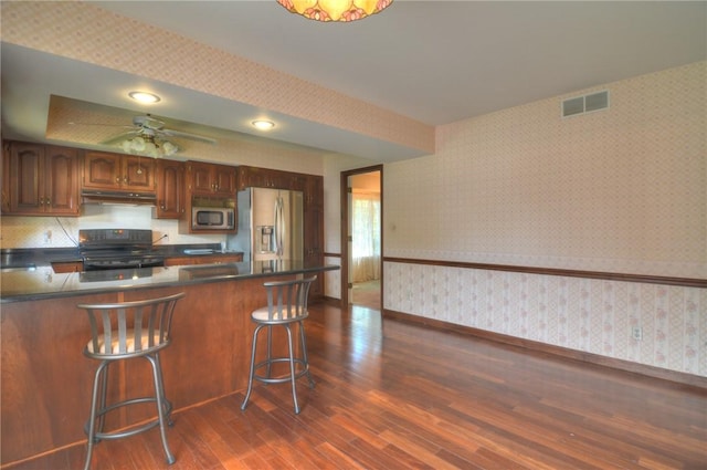 1225 W Pineview Ct, Decatur, IL 62526 - kitchen featuring wallpapered walls, appliances with stainless steel finishes, under cabinet range hood, dark wood finished floors, and a peninsula