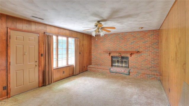 1225 W Pineview Ct, Decatur, IL 62526 - unfurnished living room featuring wooden walls, ceiling fan, carpet floors, and a brick fireplace