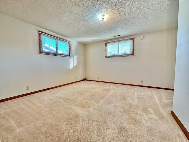 empty room with baseboards, visible vents, a wealth of natural light, and light colored carpet