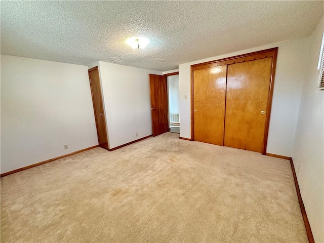 unfurnished bedroom with baseboards, a textured ceiling, a closet, and light colored carpet