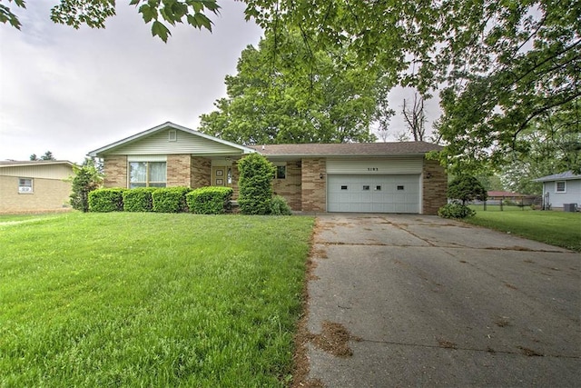 3103 N Oakland Ave, Decatur, IL 62526 - view of front of house featuring a front yard, concrete driveway, an attached garage, brick siding, and central AC