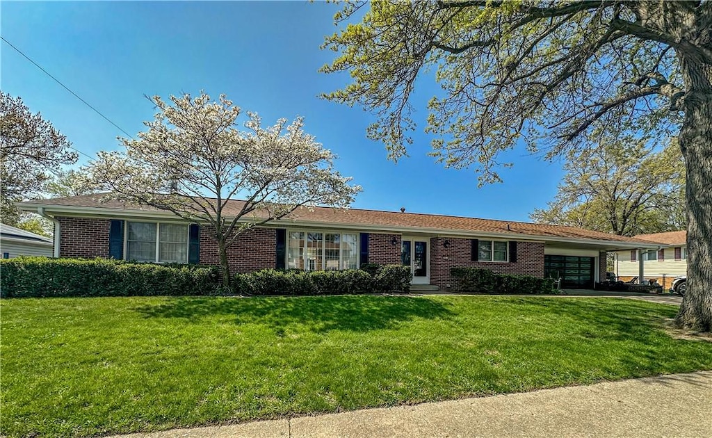 ranch-style home featuring an attached garage, a front lawn, and brick siding