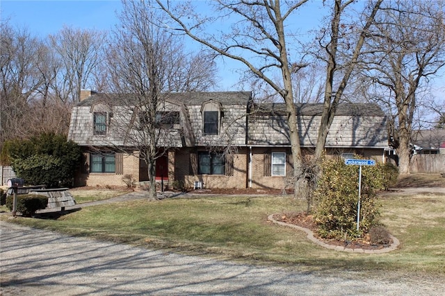 view of front of property featuring a front yard, mansard roof, and brick siding