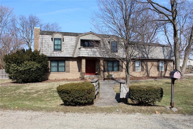 view of front of house featuring a front yard, brick siding, and a chimney