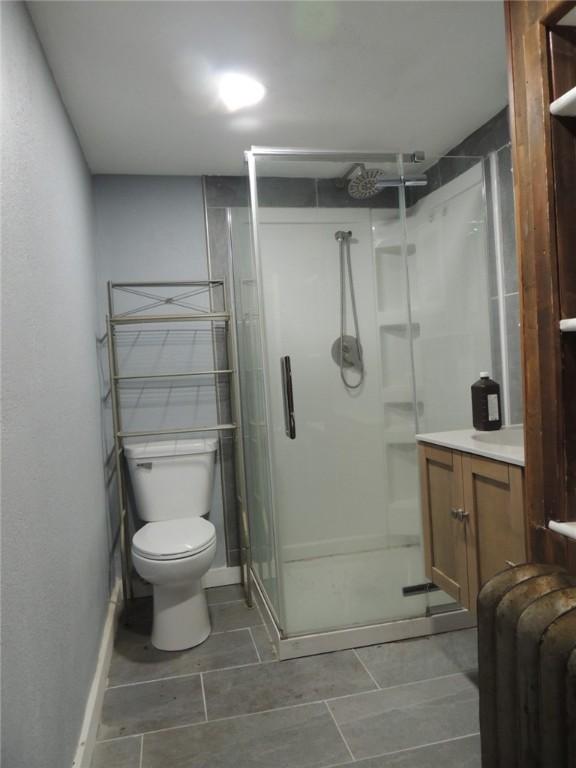 401 3rd St, Altamont, IL 62411 - bathroom featuring a stall shower, toilet, tile patterned floors, and baseboards