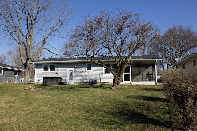 rear view of house featuring a lawn and a sunroom