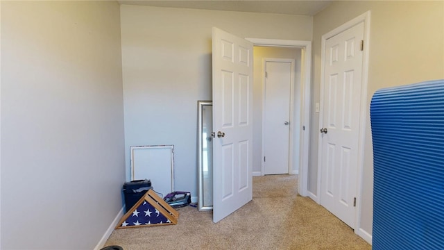 corridor featuring light colored carpet and baseboards