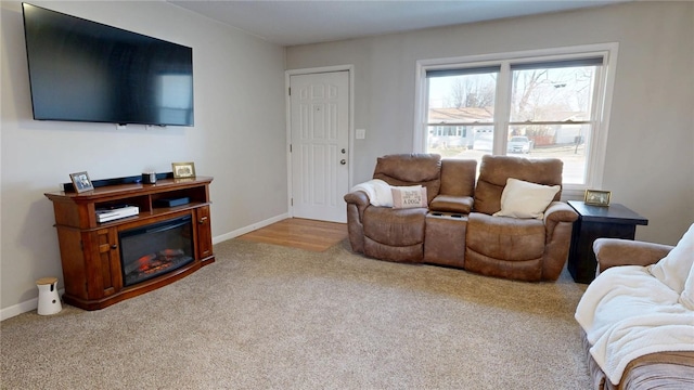 carpeted living area featuring baseboards and a glass covered fireplace