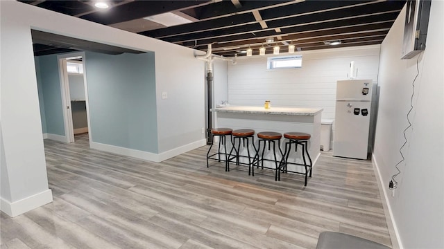 kitchen featuring white cabinetry, a kitchen bar, light wood-style floors, and freestanding refrigerator