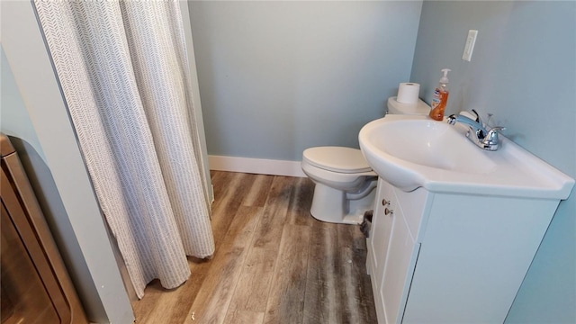 bathroom featuring toilet, vanity, baseboards, and wood finished floors