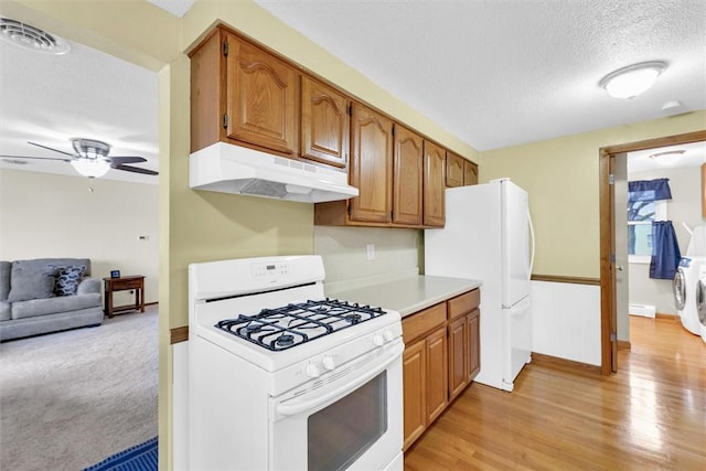 kitchen featuring light countertops, visible vents, a textured ceiling, white appliances, and under cabinet range hood