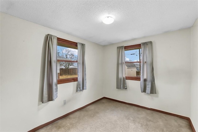 empty room featuring carpet floors, baseboards, and a textured ceiling