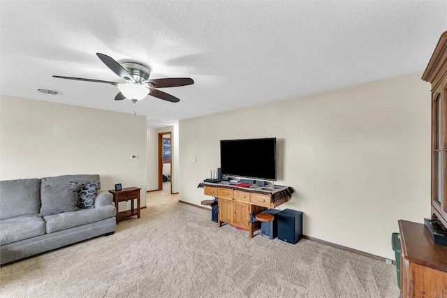 living area with a ceiling fan, visible vents, a textured ceiling, and light colored carpet