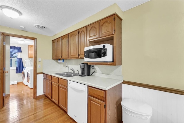 kitchen featuring washer and clothes dryer, visible vents, a sink, a textured ceiling, and white appliances