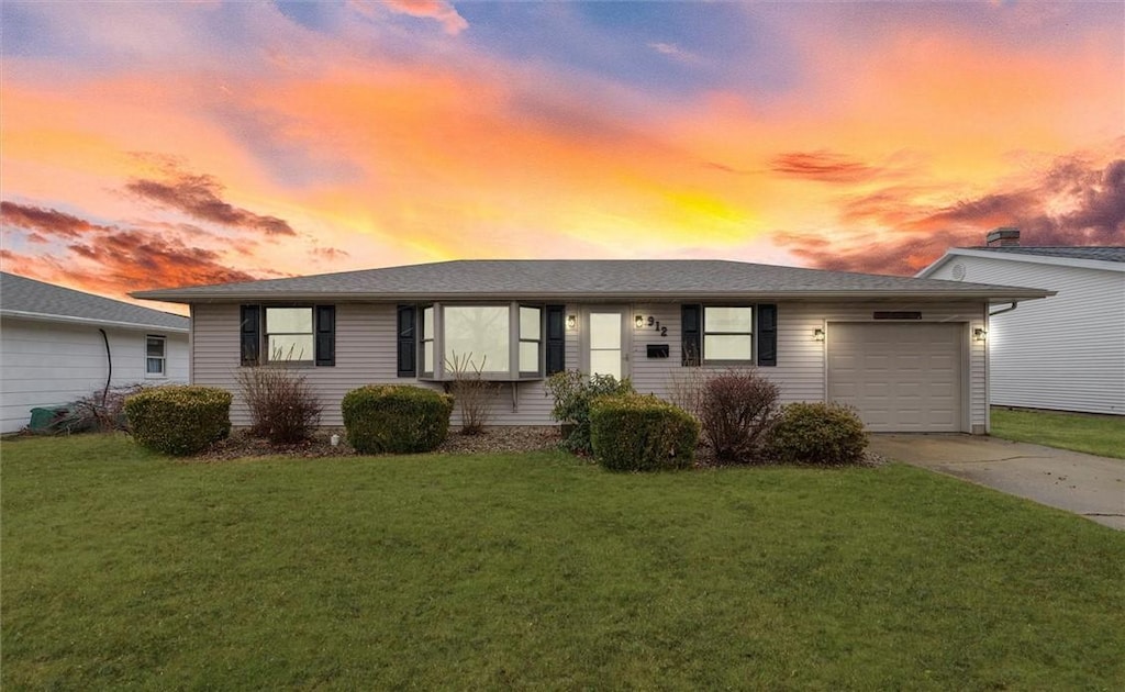 ranch-style home featuring a garage, concrete driveway, and a front lawn