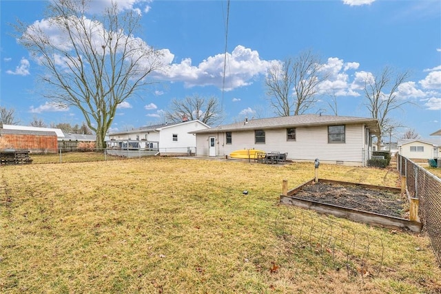 rear view of house with crawl space, a lawn, a fenced backyard, and a garden