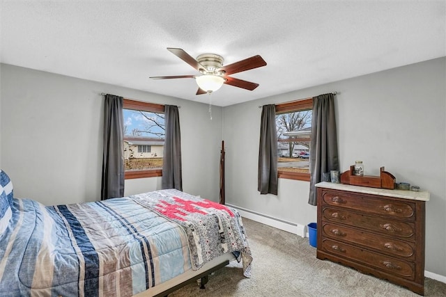 carpeted bedroom with a baseboard heating unit, multiple windows, a ceiling fan, and baseboards