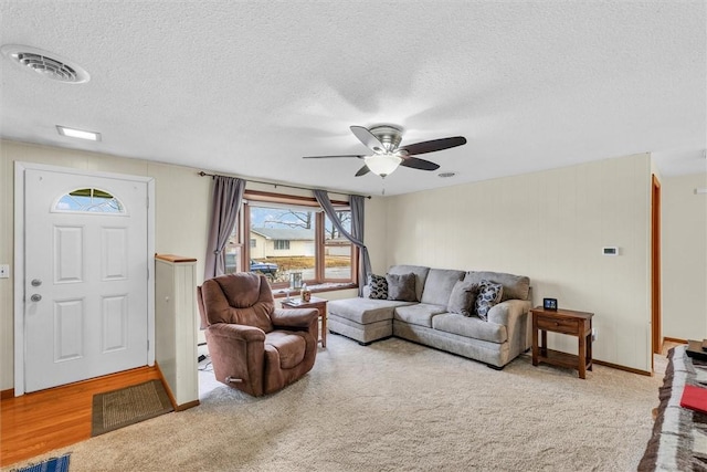 living area featuring a ceiling fan, visible vents, and a textured ceiling