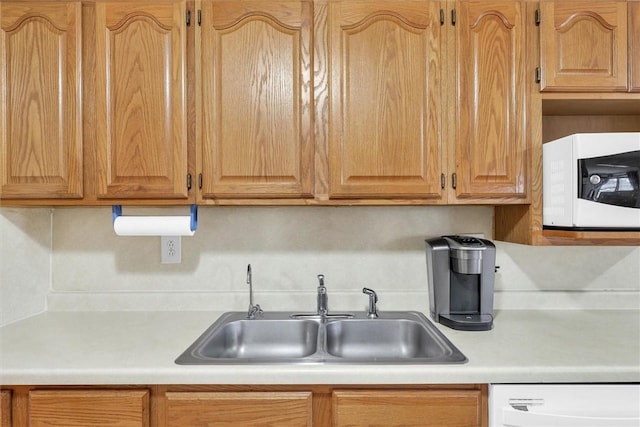 kitchen featuring white appliances, light countertops, and a sink