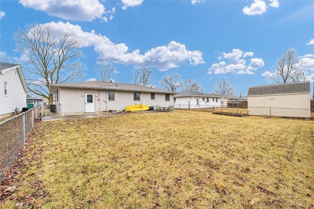 back of property featuring an outbuilding, a fenced backyard, a lawn, and a patio