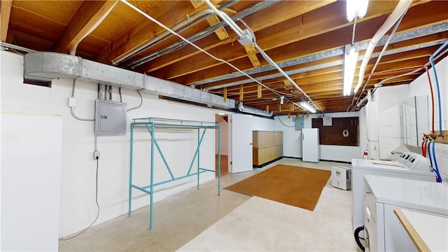 basement featuring white fridge, electric panel, and independent washer and dryer