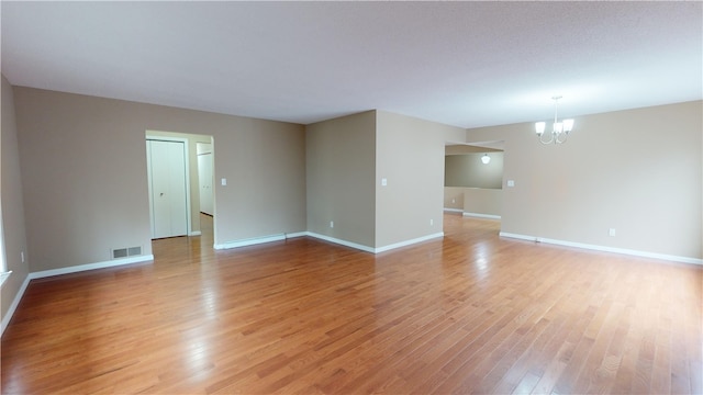 empty room with an inviting chandelier and light hardwood / wood-style floors