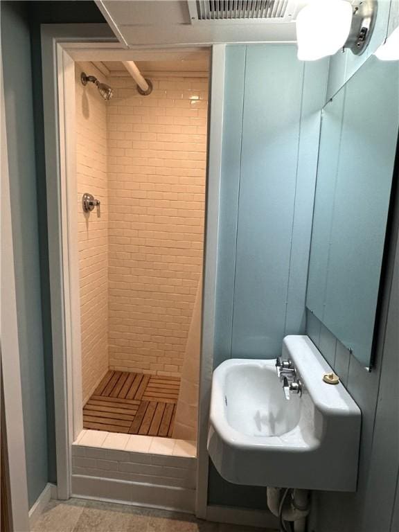 bathroom featuring a tile shower and sink