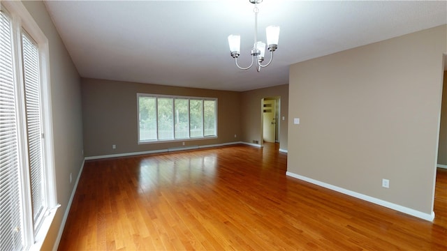 empty room with hardwood / wood-style flooring and a chandelier