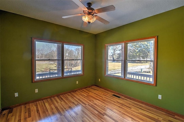 empty room with a textured ceiling, light hardwood / wood-style floors, and ceiling fan