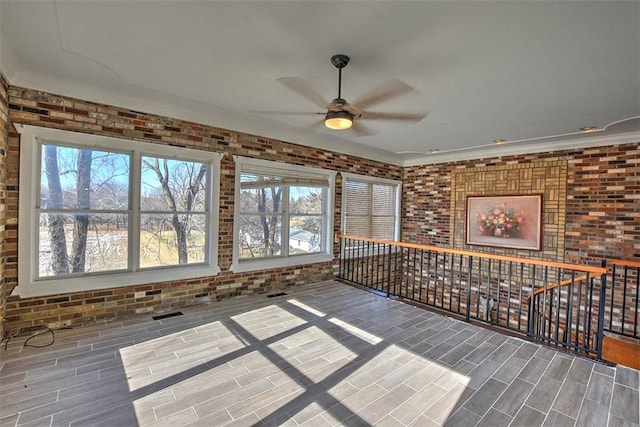 interior space with brick wall and ceiling fan