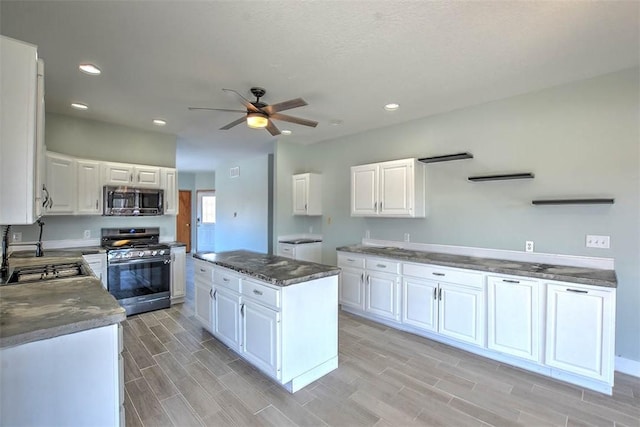 kitchen featuring sink, white cabinetry, appliances with stainless steel finishes, a kitchen island, and ceiling fan