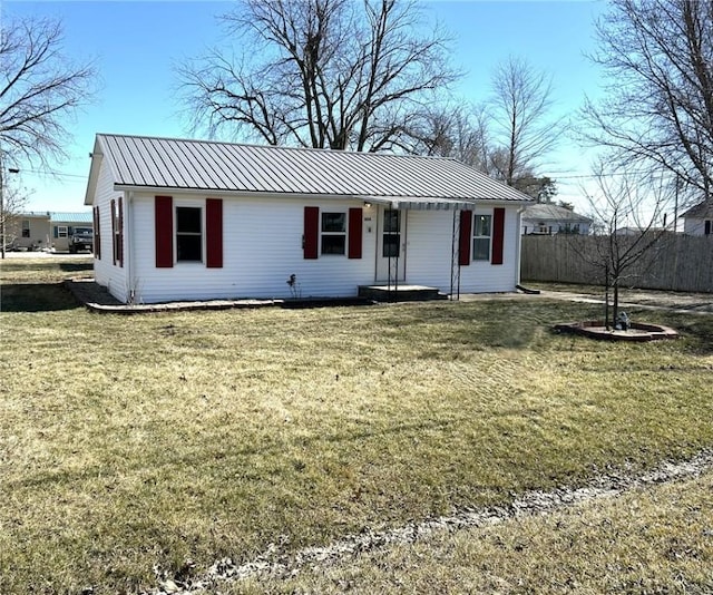 single story home featuring metal roof, a front lawn, and fence