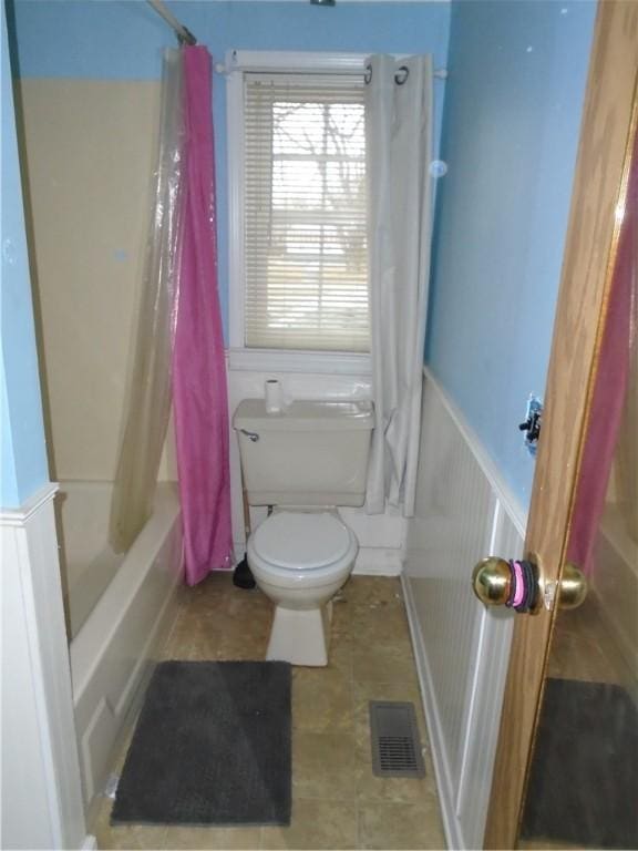 full bathroom with toilet, wainscoting, visible vents, and shower / bathtub combination with curtain