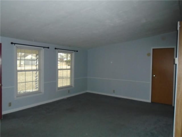 empty room featuring baseboards, dark colored carpet, and a healthy amount of sunlight