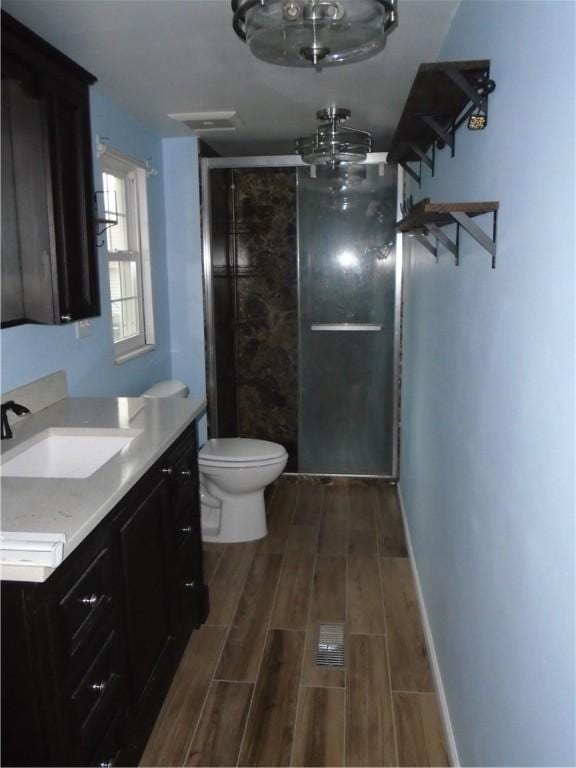 bathroom with baseboards, toilet, wood tiled floor, vanity, and a shower stall