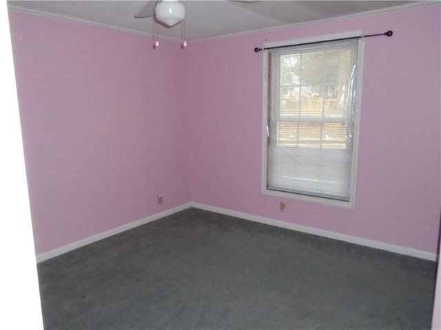 spare room with baseboards, dark carpet, and crown molding