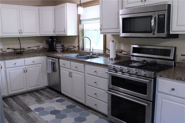 kitchen with appliances with stainless steel finishes, dark hardwood / wood-style flooring, sink, decorative light fixtures, and white cabinetry