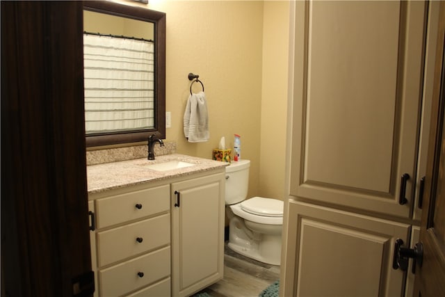 bathroom featuring toilet, vanity, and hardwood / wood-style flooring