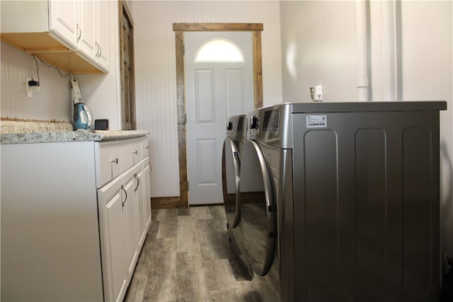 laundry area featuring cabinets, separate washer and dryer, and light hardwood / wood-style flooring