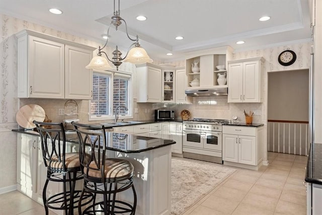 kitchen with white cabinets, appliances with stainless steel finishes, sink, hanging light fixtures, and a breakfast bar area